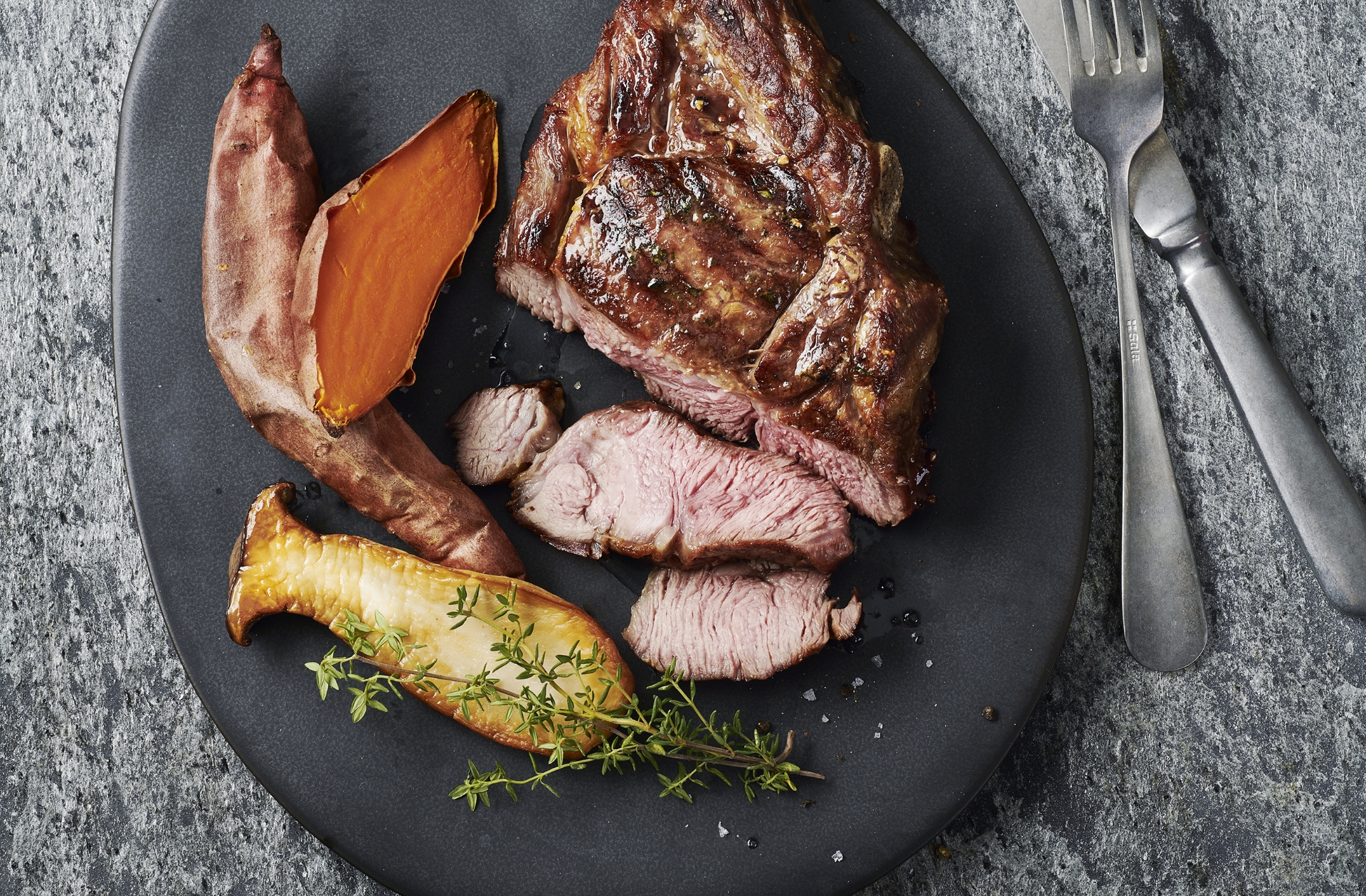 Tomahawk-Steak aufgeschnitten auf einem Teller mit Gemüsebeilage