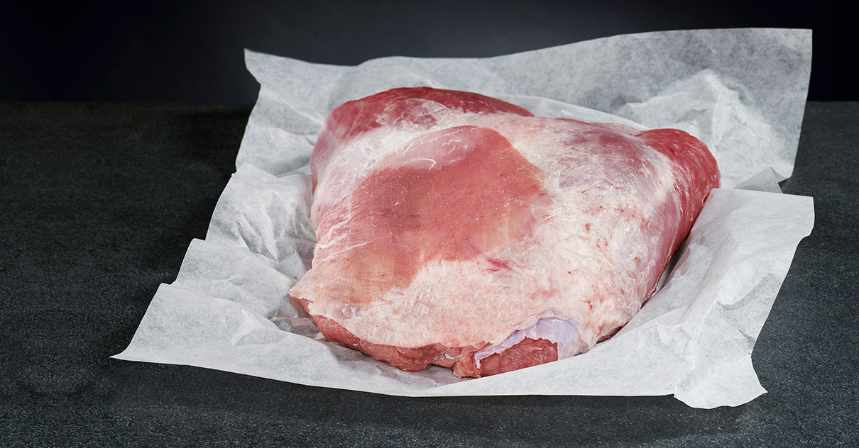 Stück Fleisch "Kalbsschulter", das auf Papier liegt